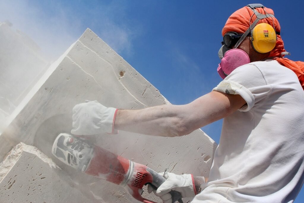 Profissional com equipamento de proteção cortando pedra com esmerilhadeira